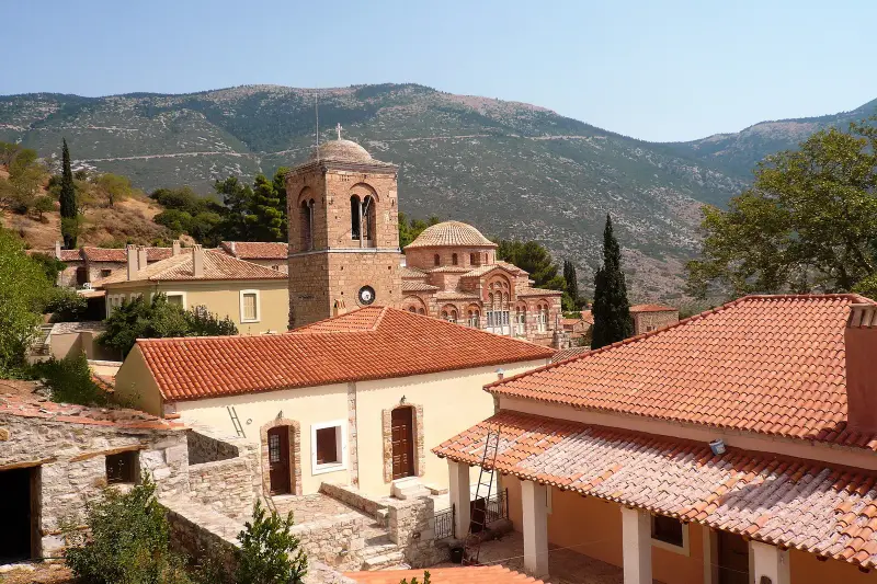The domed churches and bell tower of the Hosios Loukas monastery among red-tiled roofs, with hills rising behind
