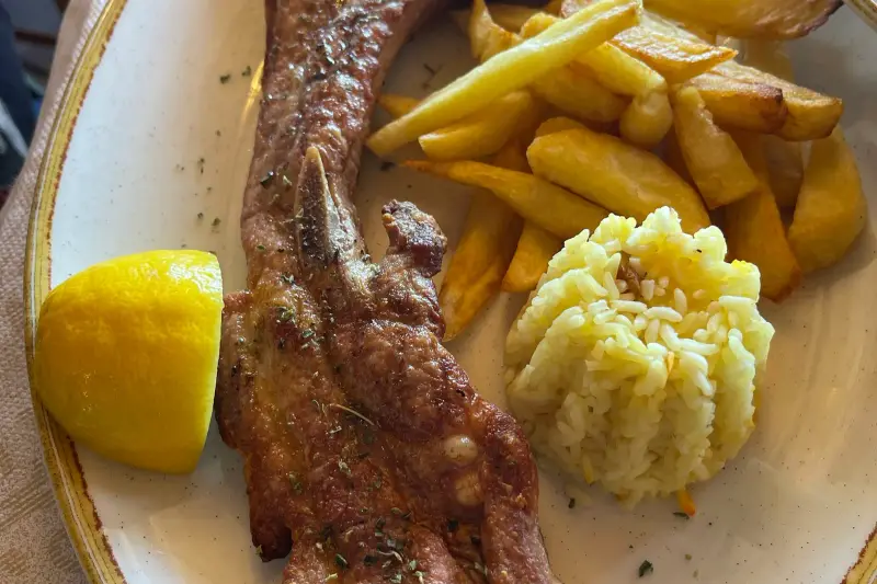 Grilled lamb chops served with french fries, rice pilaf and a lemon wedge
