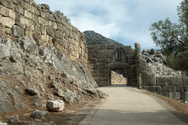 The Lion Gate at Mycenae, a massive stone archway topped by a carved relief of two lions, seen from the approach path